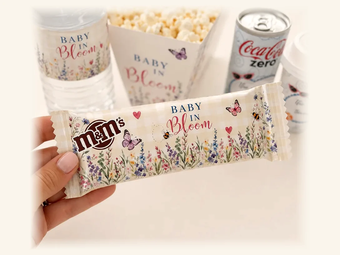 Table de fête personnalisée : bouteille, cornet de popcorn, canettes et confiseries assortis au même thème fleuri
